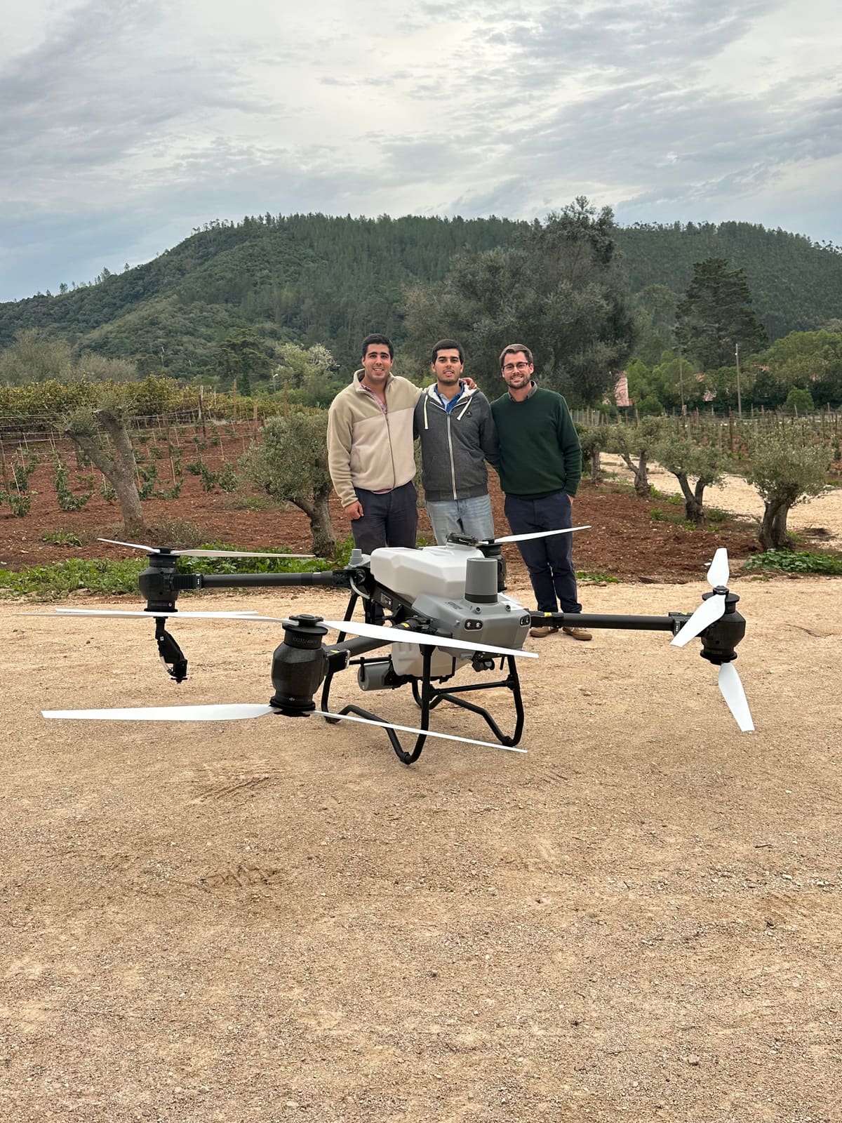 Os três sócios da Sky Agro junto a um drone agrícola, com a vinha ao fundo